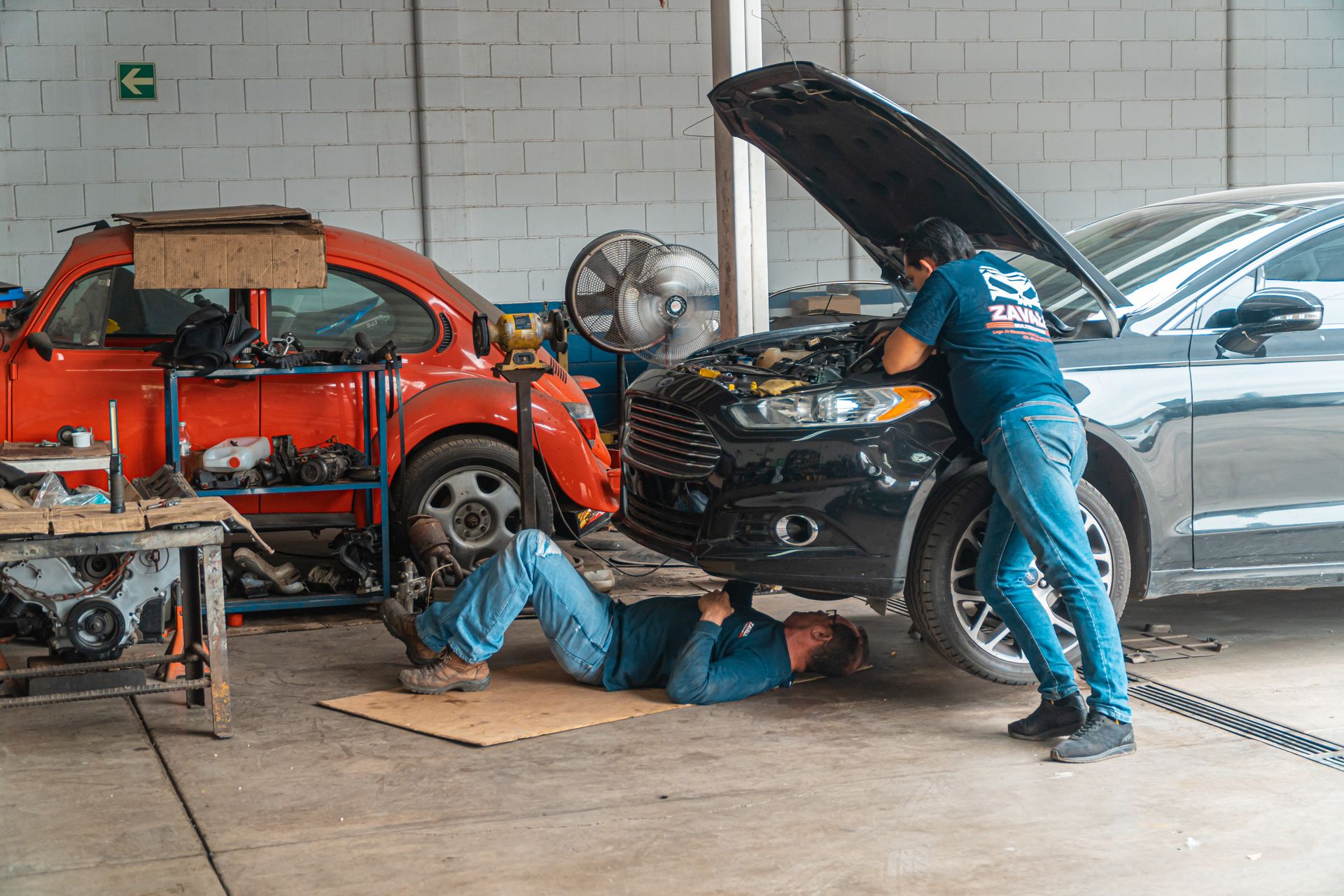 Mechanics working with vehicles in a complete workshop scene
